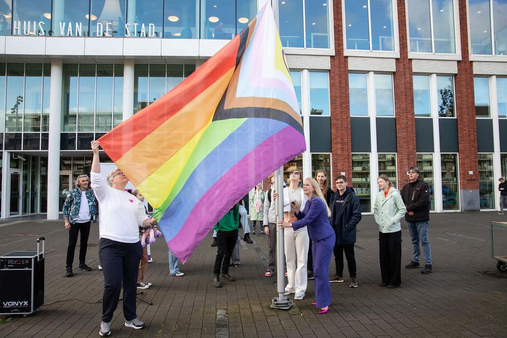 Op de foto staat wethouder Anna van Popering, die samen met een aantal inwoners de regenboogvlag hijst voor het Huis van de Stad.