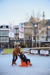 Een foto van 2 mensen op de Goudse ijsbaan rondom het Stadhuis.